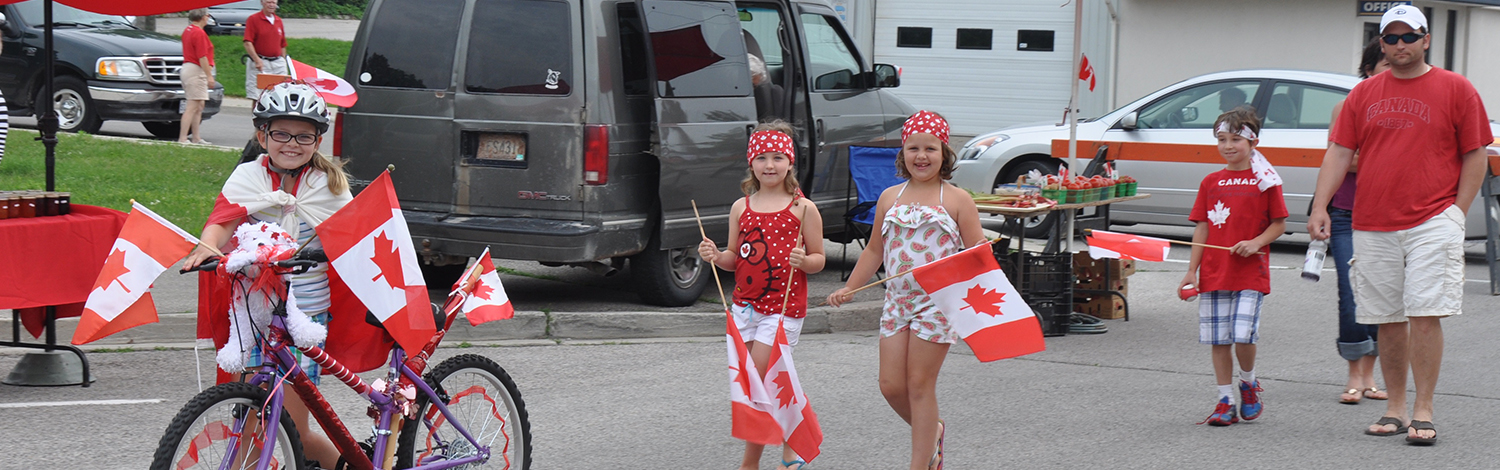 group of kids on Canada Day with decorated bikes and adults following