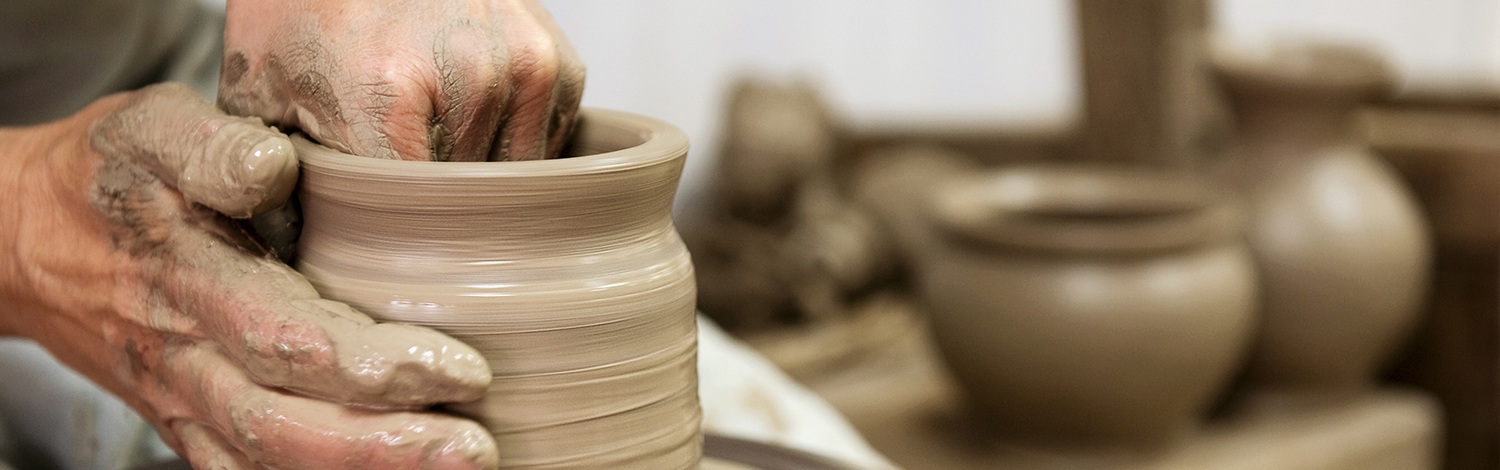 male hands doing pottery on a wheel