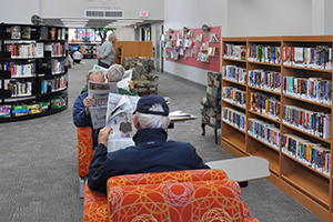 Interior of Tillsonburg Library showing stacks and patrons reading papers